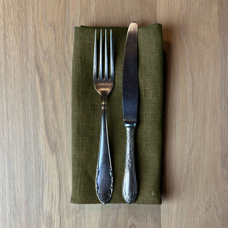 Fork-and-knife-on-olive-green-linen-napkin