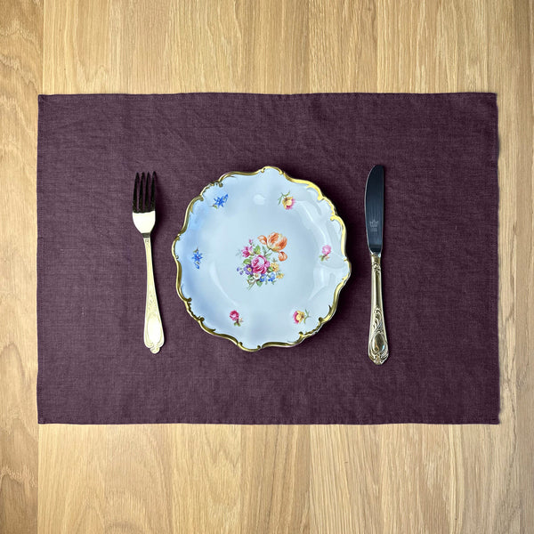 Plate-with-flowers_-knife-and-fork-on-aubergine-linen-placemat-on-wooden-table