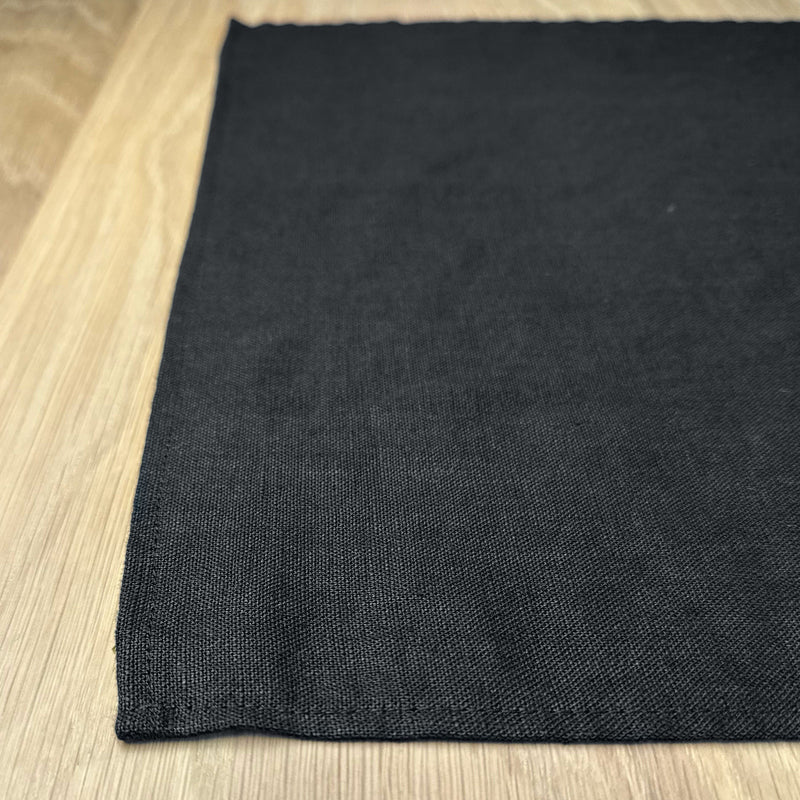 Corner-of-black-linen-placemat-on-wooden-table