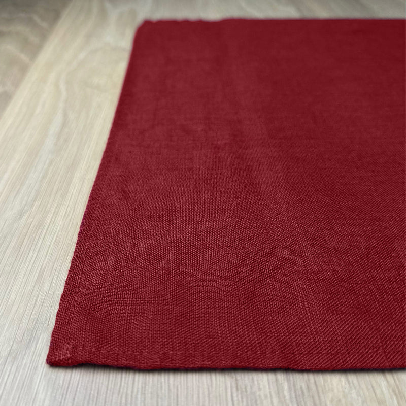 Corner-of-carmine-red-linen-placemat-on-wooden-table