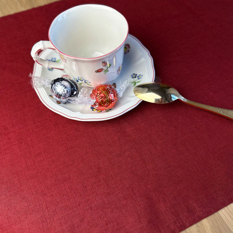 Cup_-plate-and-spoon-with-candys-on-Carmine-red-linen-placemat-on-wooden-table
