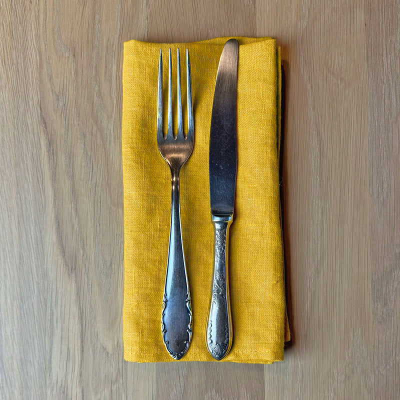 Fork-and-knife-on-sunny-yellow-linen-napkin