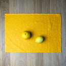 Orange and lemon on Sunny yellow linen placemat on wooden table.