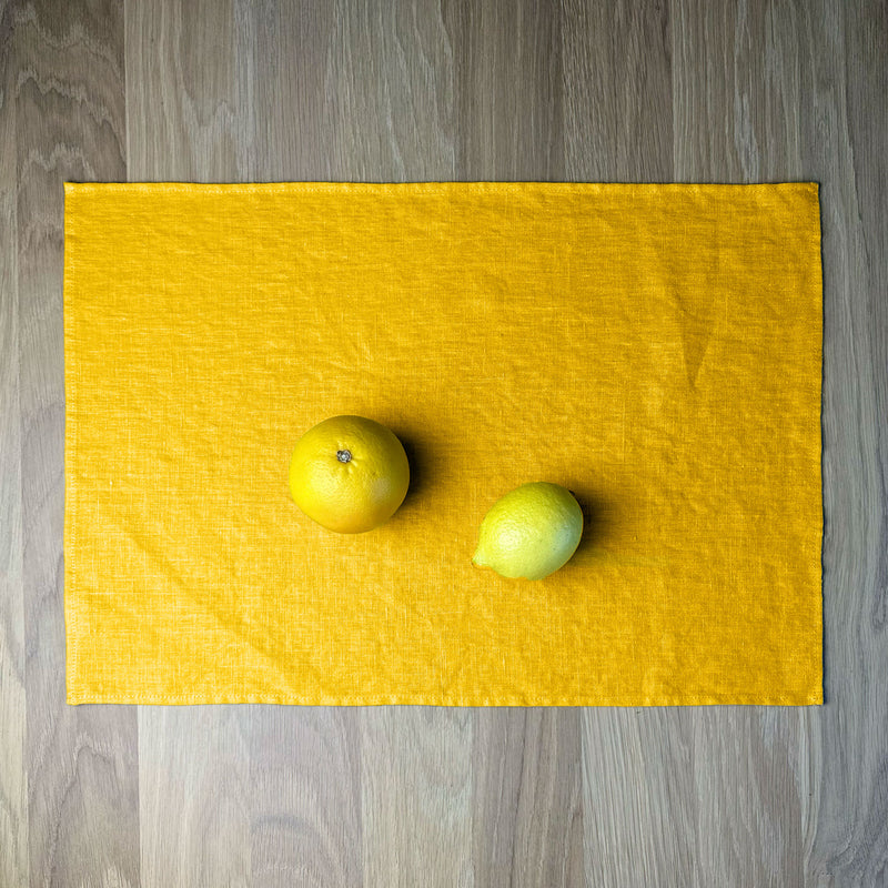 Orange and lemon on Sunny yellow linen placemat on wooden table.