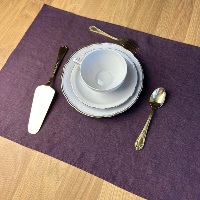 Plate-knife-and-fork-on-aubergine-linen-placemat-on-wooden-table