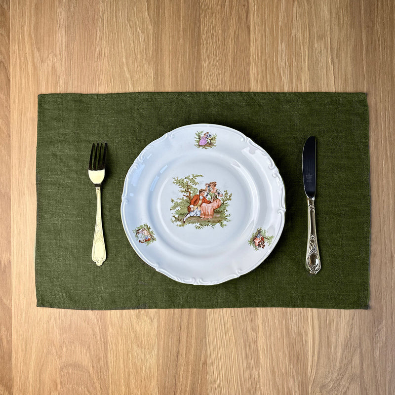 Plate-with-Man-and-woman_-fork-and-knife-on-olive-green-linen-placemat-on-wooden-table