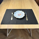 Plate-with-flowers_-fork-and-knife-on-black-linen-placemat-on-wooden-table