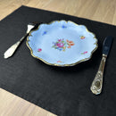 Plate-with-flowers_-fork-and-knife-on-black-linen-placemat-on-wooden-table