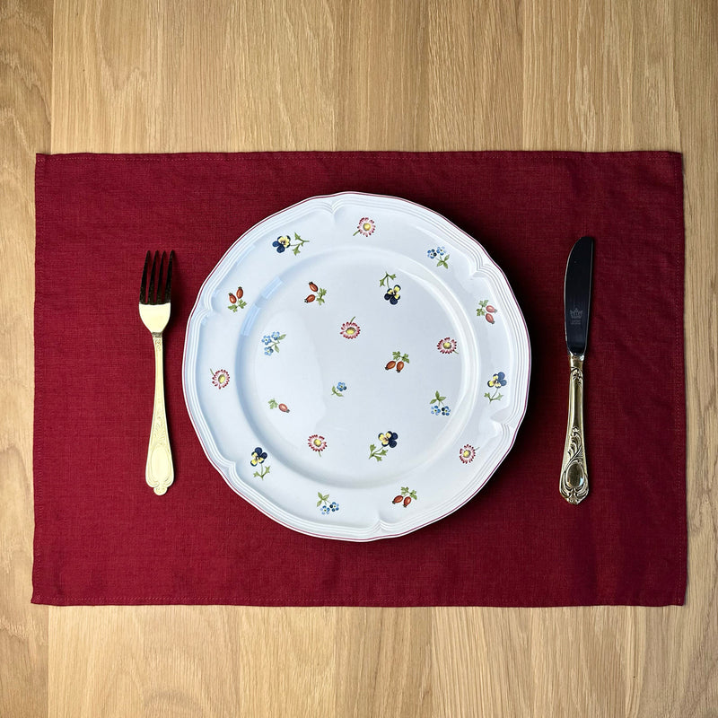 Plate-with-flowers_-knife-and-fork-on-Carmine-red-linen-placemat-on-wooden-table