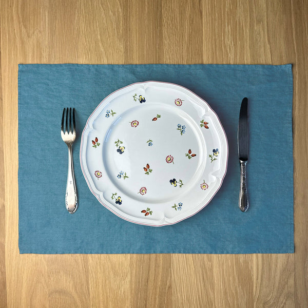 Plate-with-flowers_-knife-and-fork-on-petrol-linen-placemat-on-wooden-table