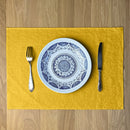 Plate-with-pattern_-fork-and-knife-on-Sunny-yellow-linen-placemat-on-wooden-table