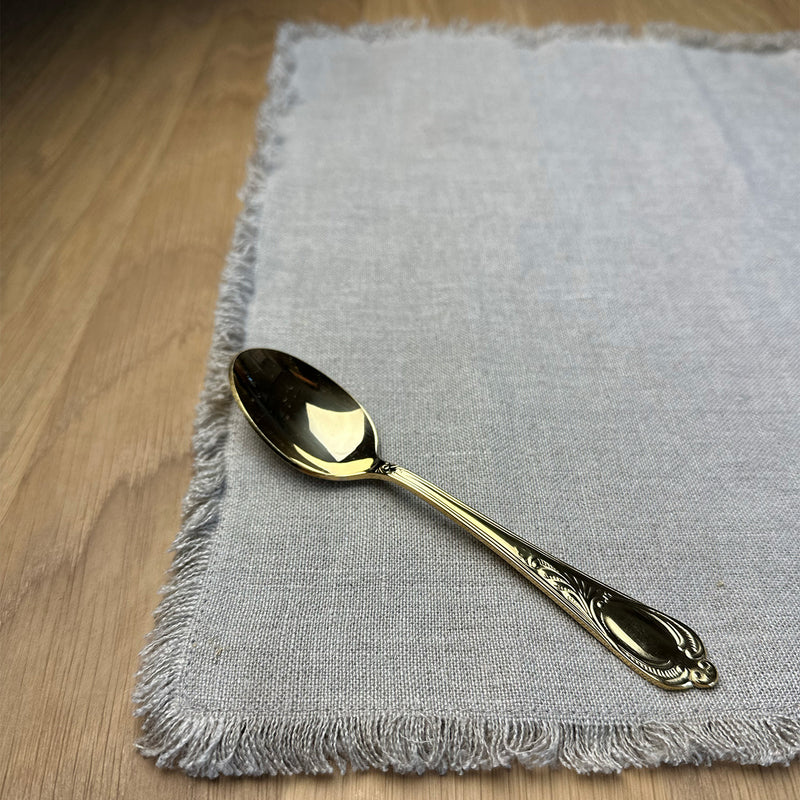 Small spoon on natural gray Linen placemat on wooden table