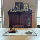 antique cabinet with dishes and natural gray linen placemat with a cezve and a candlestick with a candle