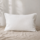 White linen pillowcase on natural linen bedding in soft morning light

