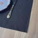 Plate-with-flowers_-fork-and-knife-on-black-linen-placemat-on-wooden-table