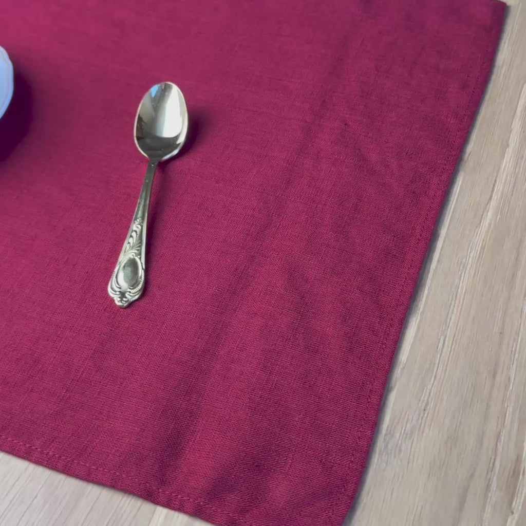 Cup,-plate-and-spoon-with-candys-on-Carmine-red-linen-placemat-on-wooden-table