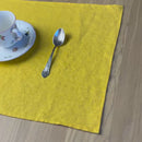 Plate-with-pattern_-fork-and-knife-on-Sunny-yellow-linen-placemat-on-wooden-table